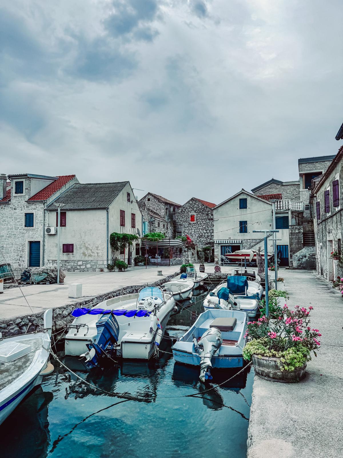 Mały port z łódkami i kamienną zabudową na Wyspie Murter